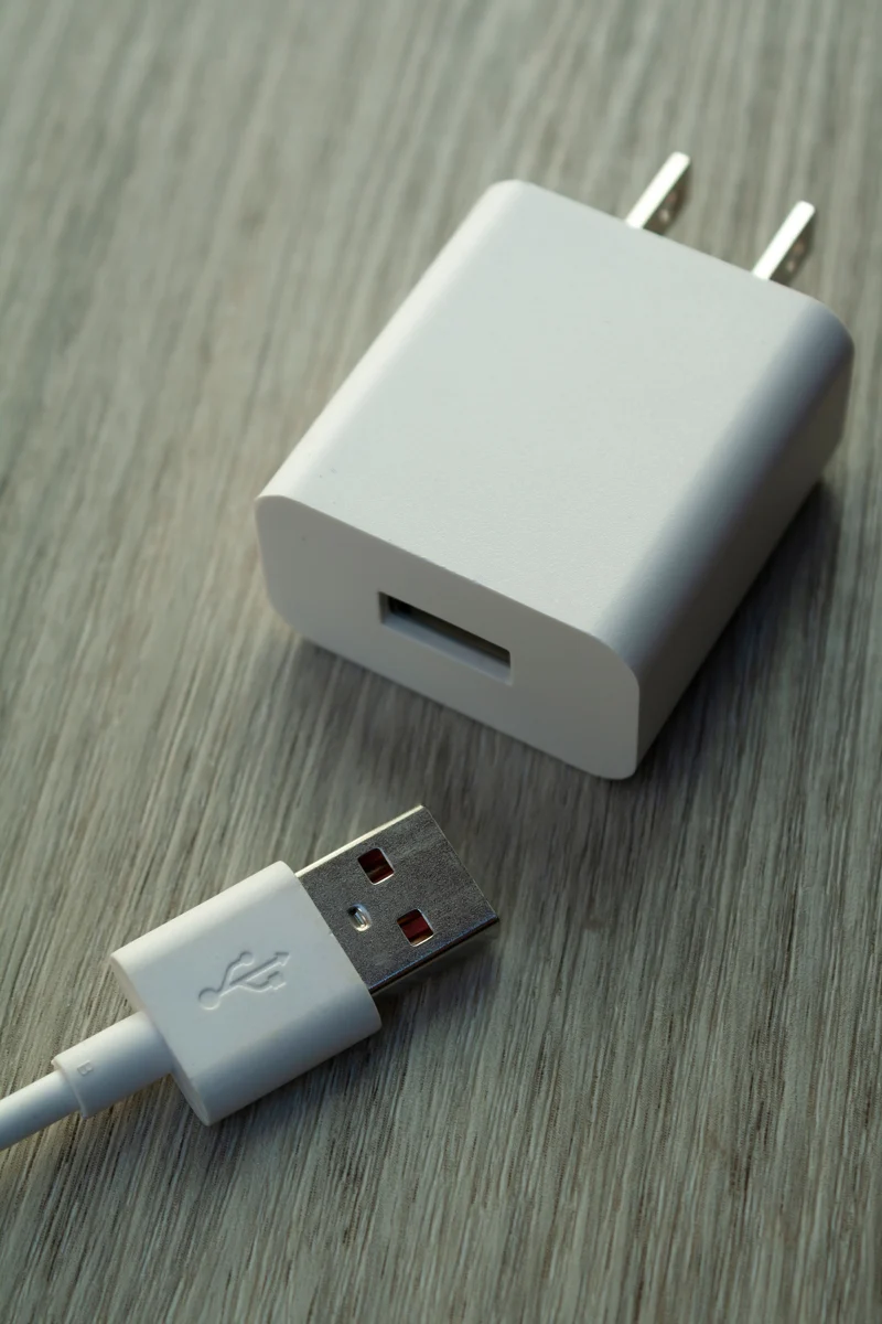White USB wall charger and cable on a wooden surface