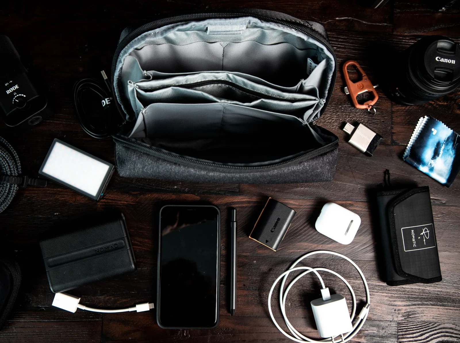 Travel pouch, phone, power bank, charging cables and camera accessories on a desk