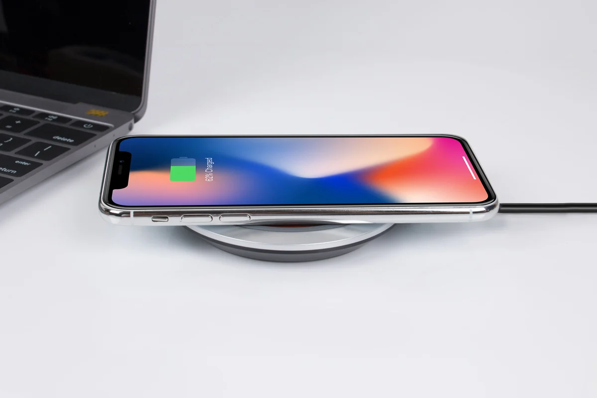 Phone resting on a wireless charging pad beside a laptop
